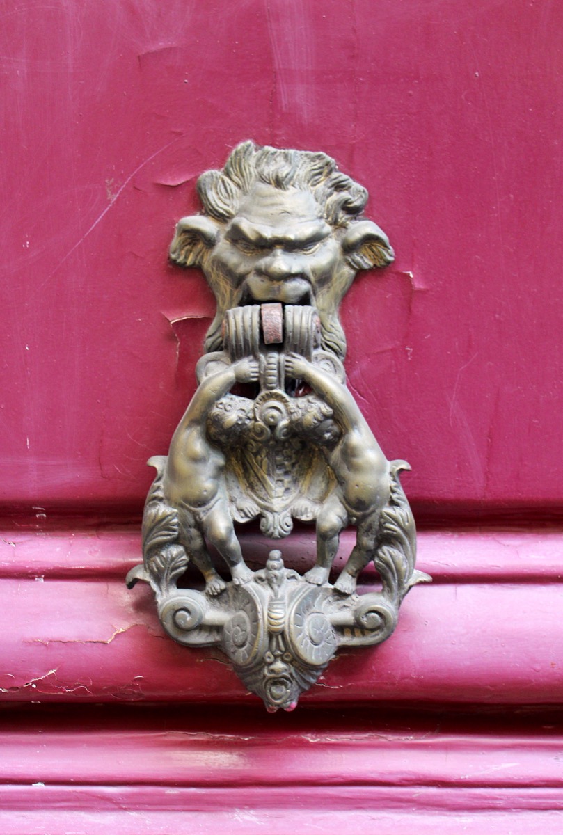 Figurative metal door knocker on a pink door